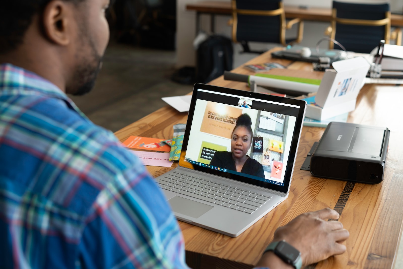 man in blue and white plaid shirt using macbook pro